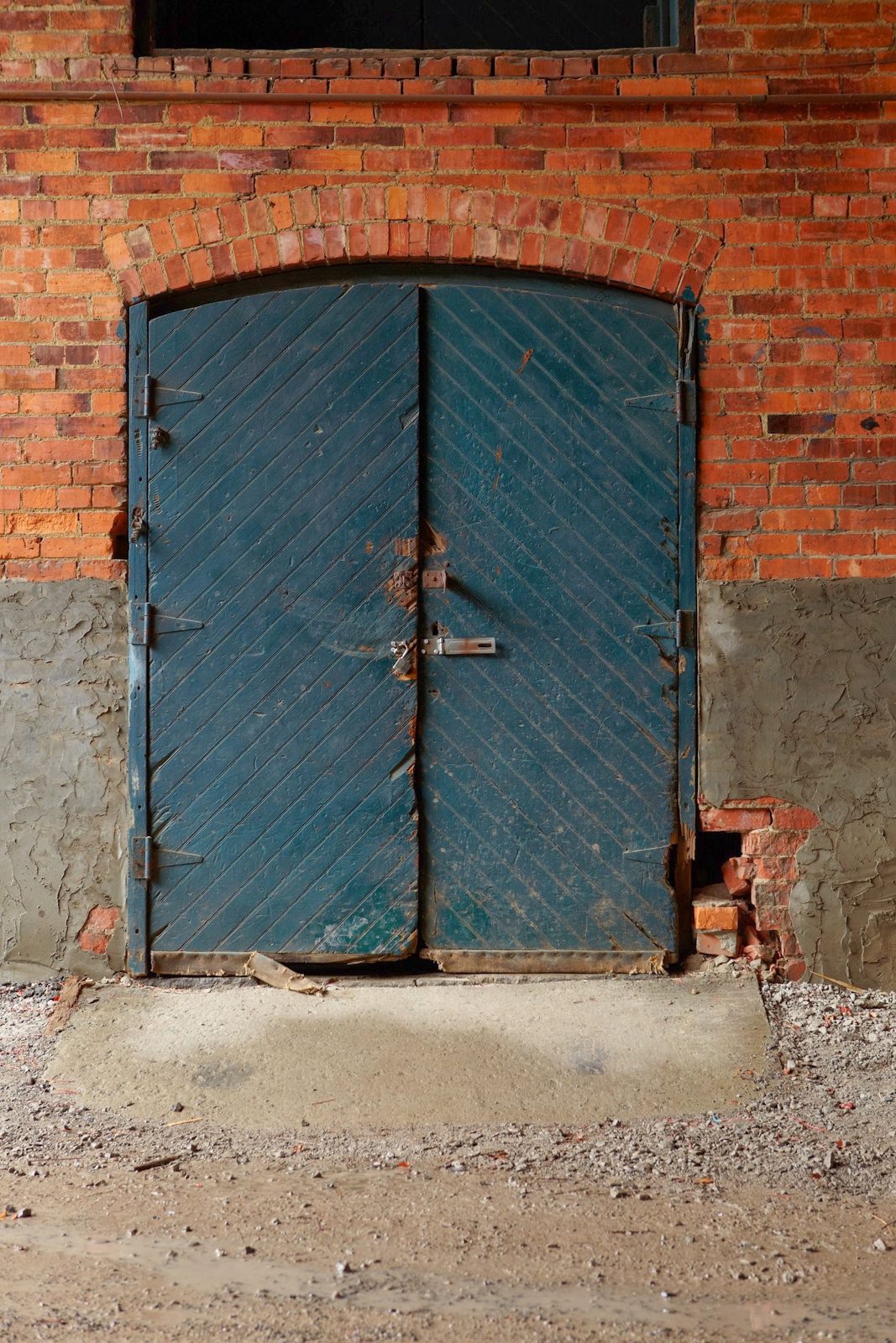 Teal double door set into a brick archway