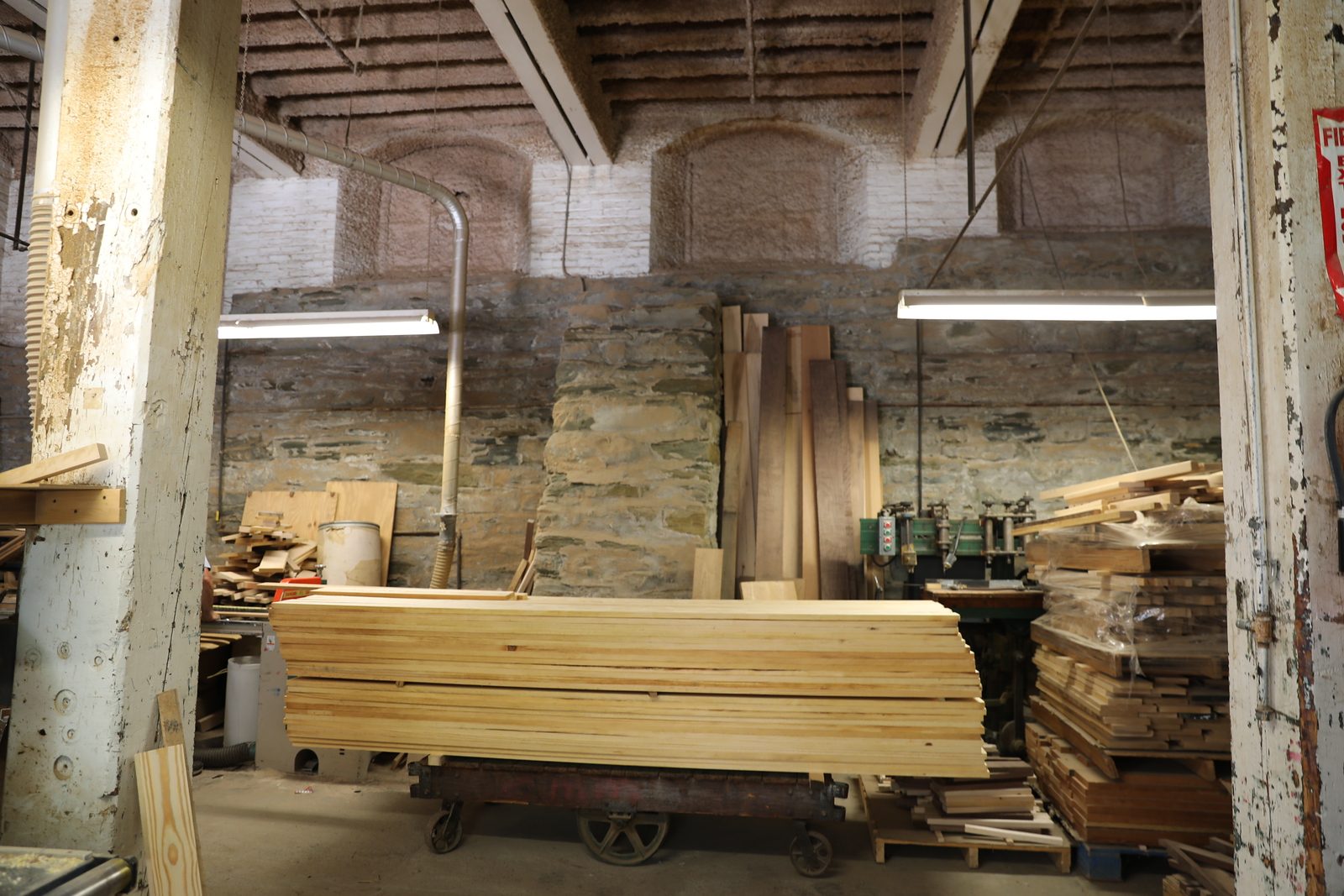 Milling machine with stacked lumber against a stone wall