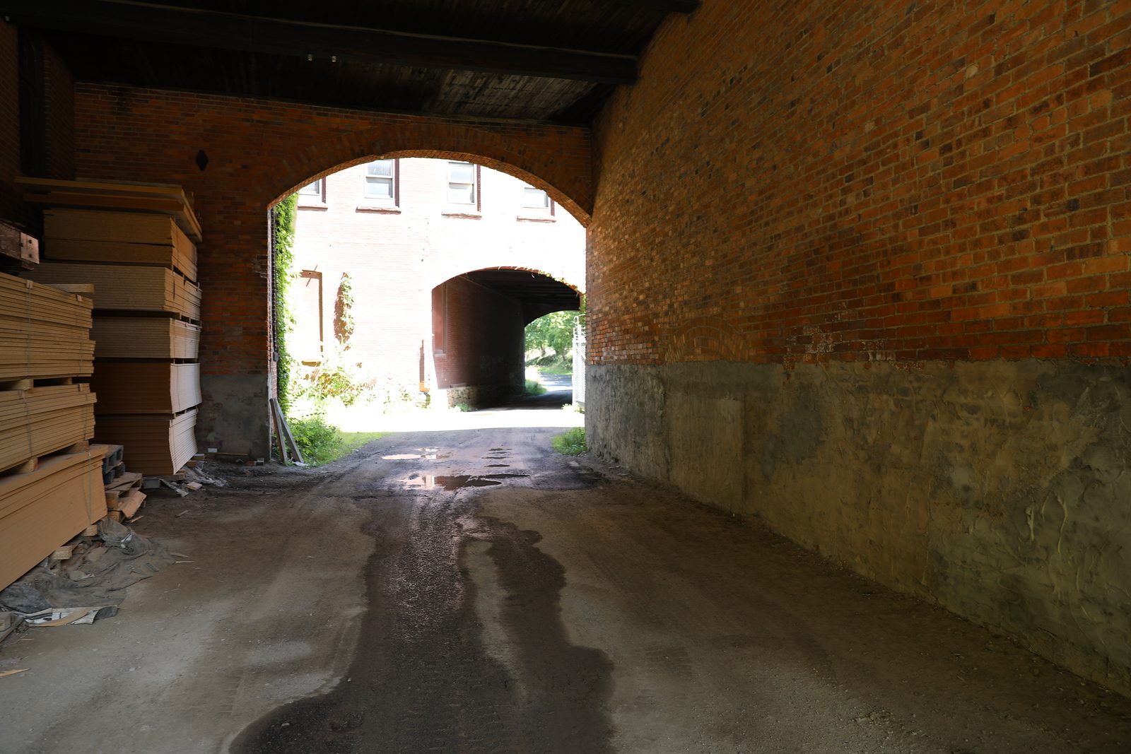 Brick archway passage with lumber stacked to one side